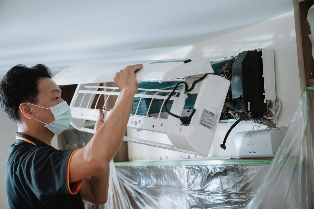 騰芸空調技師小心拆卸分離式冷氣外殼，施工現場以防水布與塑膠膜全面防護，並架設集水導流系統，確保施工過程安全、無污染。