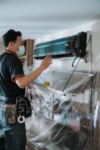 騰芸空調技師小心拆卸分離式冷氣外殼，施工現場以防水布與塑膠膜全面防護，並架設集水導流系統，確保施工過程安全、無污染。