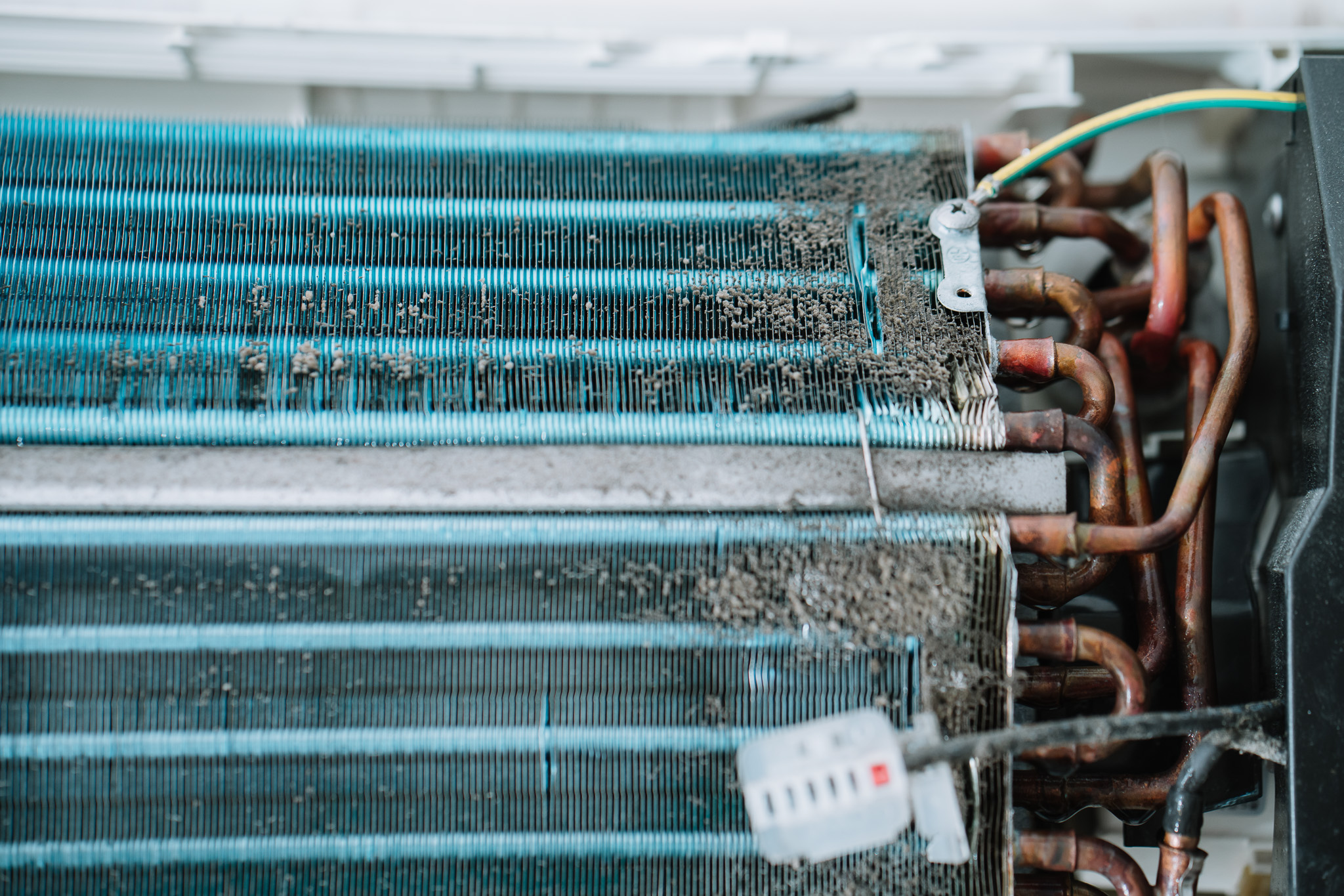 冷氣風鼓與冷凝器堆滿灰塵與黴菌，厚厚的棉絮層明顯可見，顯示長期未清洗導致的空氣污染與效率下降問題。