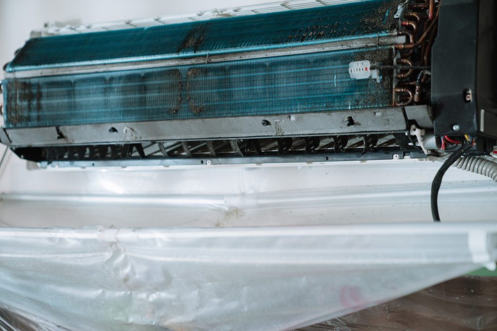 冷氣風鼓與冷凝器堆滿灰塵與黴菌，厚厚棉絮層清晰可見，顯示長期未清洗造成的空氣污染與效能下降。